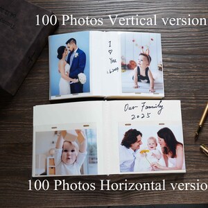 Pode incluir: Um &aacute;lbum de fotos castanho escuro com um desenho de cruz e o texto "100 Photos Vertical version". O &aacute;lbum est&aacute; aberto, exibindo fotos de fam&iacute;lia e notas manuscritas. Uma caneta dourada repousa sobre uma superf&iacute;cie de madeira.