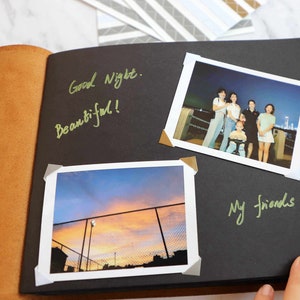 May include: A black scrapbook with two photos. The first photo shows a group of friends standing together at night. The second photo shows a sunset over a fence. The scrapbook has the words "Good Night. Beautiful!" and "My friends!" written on it.