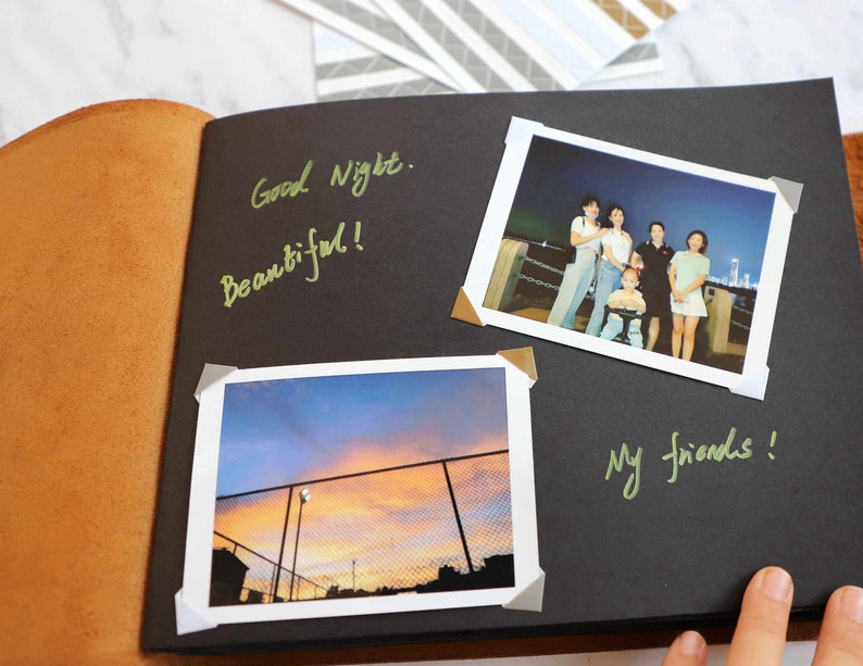 May include: A black scrapbook with two photos. The first photo shows a group of friends standing together at night. The second photo shows a sunset over a fence. The scrapbook has the words "Good Night. Beautiful!" and "My friends!" written on it.