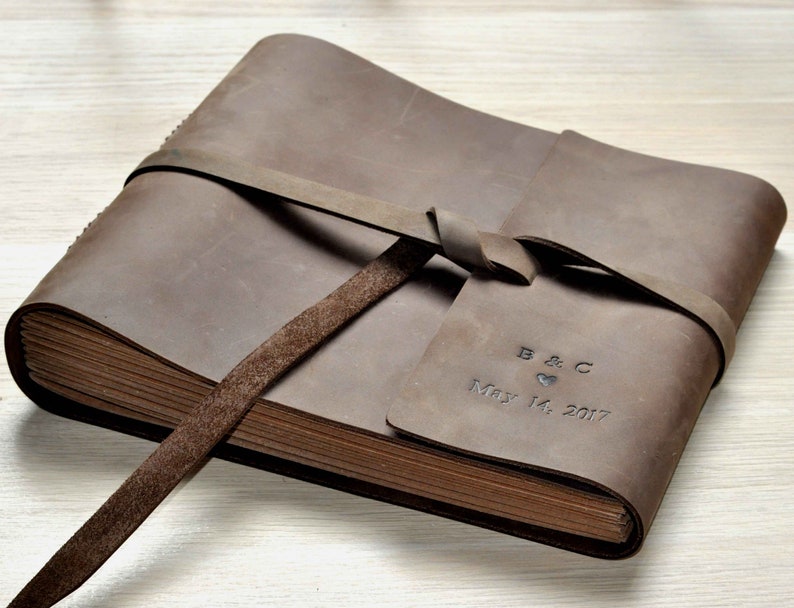 May include: A brown leather-bound photo album with a tied closure and personalized inscription: "B & C May 14, 2017".