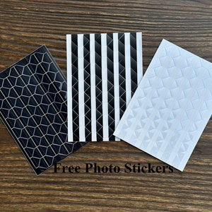 May include: Three sheets of photo corner stickers. One sheet has a black and white striped pattern, one sheet has a black honeycomb pattern, and one sheet has a white diamond pattern. Free Photo Stickers.