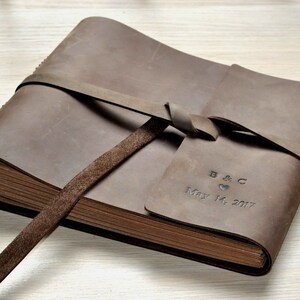 May include: A brown leather-bound photo album with a tied closure and personalized inscription: "B & C May 14, 2017".