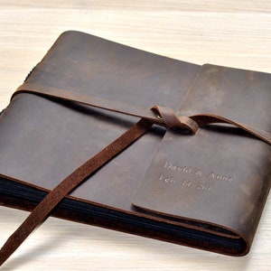 May include: A brown leather photo album with a tied closure and personalized inscription: "David & Anna Feb. 14, 2017".