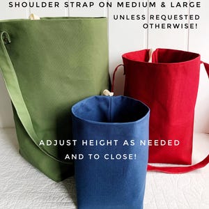 May include: Three fabric tote bags in green, red, and blue. The green bag has a shoulder strap. The text on the image reads: "SHOULDER STRAP ON MEDIUM & LARGE UNLESS REQUESTED OTHERWISE! ADJUST HEIGHT AS NEEDED AND TO CLOSE!"