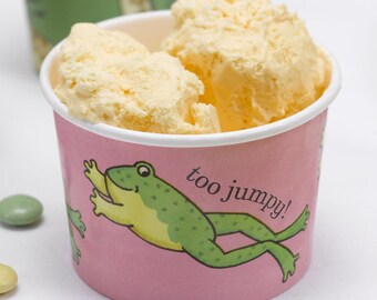 May include: A pink paper ice cream cup with a green frog illustration and the text "too jumpy!"  The cup is filled with vanilla ice cream.