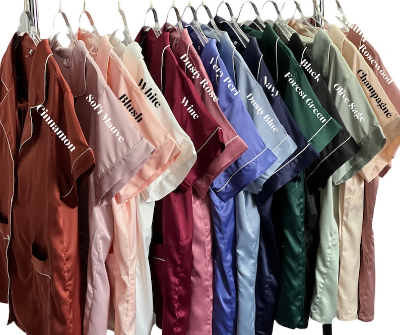 May include: A collection of satin pajama sets in various colors, including cinnamon, soft mauve, blush, white, wine, dusty rose, very peri, dusty blue, navy, forest green, black, olive sage, champagne, and rosewood. Each set has white trim.