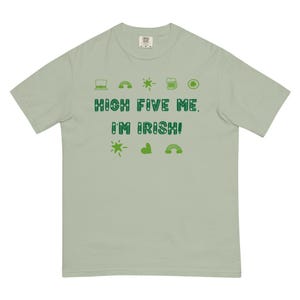 May include: A light green t-shirt with the text "HIGH FIVE ME. I'M IRISH!" in green. The shirt is decorated with green shamrocks, rainbows, beer mugs, and stars.