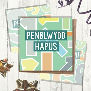 Puede incluir: Una tarjeta verde con un patrón geométrico colorido y el texto "PENBLWYDD HAPUS" en blanco. La tarjeta es una tarjeta de cumpleaños.