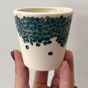 Op de afbeelding: Een witte keramische mok met een zwart handvat en de tekst "But First, Coffee" in handschriftstijl. De mok staat op een wit oppervlak. De mok is ongeveer 10 cm hoog.