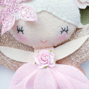 A pink felt fairy with gold glitter wings, a pink flower on her dress, and a pink glitter flower on her head.