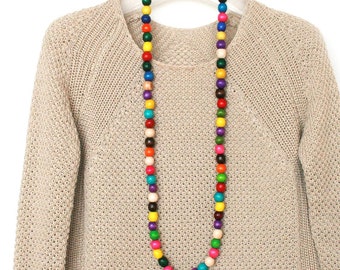 May include: A long, colorful necklace made of wooden beads. The beads are in a variety of colors, including red, orange, yellow, green, blue, purple, and brown. The necklace is hanging on a white hanger against a white background.