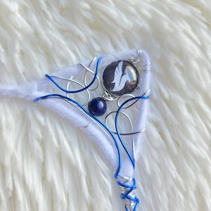Peut inclure: Un serre-tête blanc et bleu fait à la main avec un emblème de colombe. Le serre-tête présente une base blanche enveloppée de fil argenté et bleu, une perle bleue et un emblème circulaire avec une colombe blanche sur fond noir.