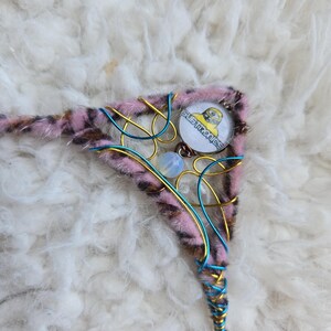 May include: A pink and brown fur-trimmed triangle-shaped wire wrapped pendant with a gold and blue wire design. The pendant features a round glass charm with a yellow cartoon character and the text "SUPER SAIYAN".