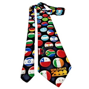 May include: A black necktie featuring a repeating pattern of circular smiley faces designed with various national flag colors and patterns. The lower portion of the tie displays the yellow text "WORLD PEACE 2000" with smiley faces replacing the zeros.