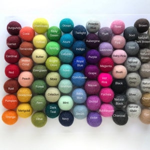 May include: A collection of colorful felt balls in various shades, including red, blue, green, and purple. Each ball is labeled with its color name, such as "Chartreuse," "Ocean," and "Burgundy." The balls are arranged in a grid, showcasing a wide range of hues.