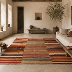 Könnte beinhalten: Ein großer, rechteckiger Teppich mit Streifenmuster in Rot-, Orange-, Braun-, Schwarz- und Blautönen. Der Teppich befindet sich in einem Wohnzimmer mit neutraler Farbgebung, einem weißen Sofa und Holzmöbeln. Abmessungen: ca. 200cm x 300cm.
