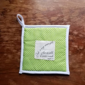 May include: Green and white pot holder with white polka dots. It has a white fabric border and a white tag with the text "God is my strength. He is all I ever need. - Psalm 73"