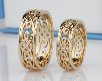 Könnte beinhalten: Zwei goldene Eheringe mit filigranen keltischen Knotenmustern. Ein Ring ist mit kleinen, klaren Edelsteinen besetzt.