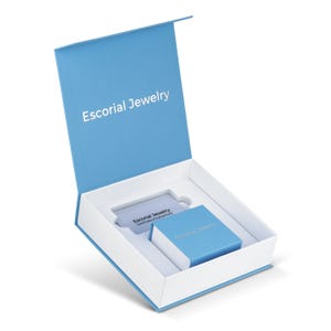 Op de afbeelding: Een lichtblauw sieradendoosje met een witte binnenkant, voorzien van de tekst Escorial Jewelry op het deksel. Binnenin bevinden zich een kleiner bijpassend blauw doosje en een rechthoekige kaart met de tekst Escorial Jewelry Certificate of Authenticity.