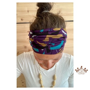Può includere: Un cerchietto viola con un motivo astratto colorato. Il cerchietto è realizzato in un tessuto morbido ed elastico, ideale per tenere i capelli fuori dal viso.
