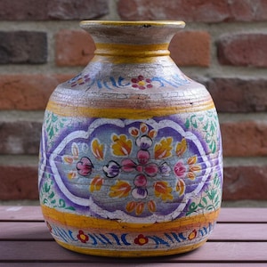 Peut inclure: Un vase en céramique arrondi présentant une finition craquelée et vieillie avec des motifs floraux peints à la main en jaune, violet, vert et rouge. Le récipient possède un corps large, un col étroit et un bord évasé, orné de motifs décoratifs.