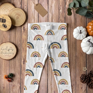 May include: White leggings with a repeating pattern of colorful rainbows. The rainbows are made up of red, orange, yellow, green, blue, indigo, and violet stripes. The leggings are a great addition to any child's wardrobe.