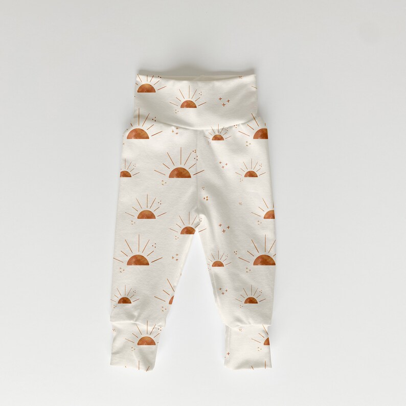 May include: White baby leggings with a brown sun and star pattern.