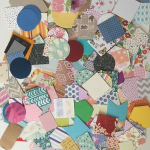 May include: A collection of colourful patterned paper scraps in various shapes and sizes, including circles, squares, and rectangles. The papers feature a variety of designs, such as polka dots, stripes, floral patterns, and geometric shapes.