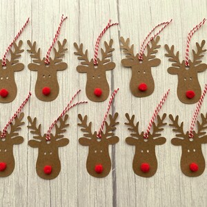 May include: Twelve brown paper reindeer gift tags with red pom-poms for noses and red and white twine.