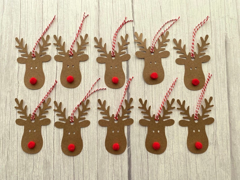 May include: Twelve brown paper reindeer gift tags with red pom-poms for noses and red and white twine.
