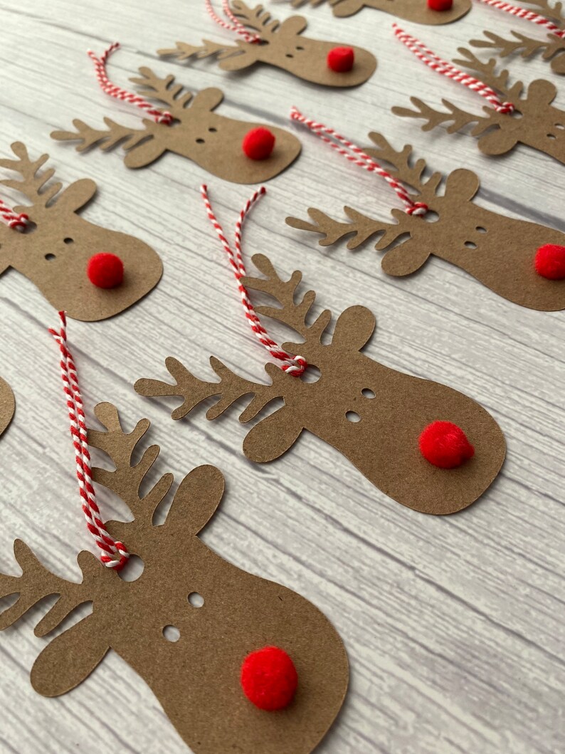 May include: A set of brown paper reindeer gift tags with red pom-poms for noses and red and white twine.