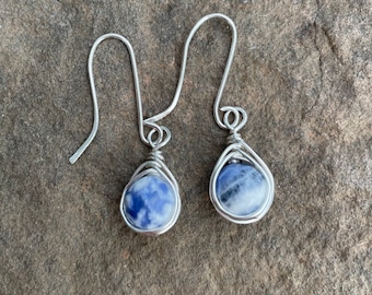 May include: A pair of silver wire wrapped earrings with blue and white sodalite stones.