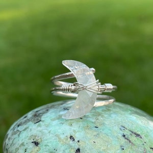 May include: A silver wire wrapped ring with a clear crescent moon shaped crystal.