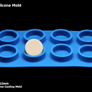 May include: Blue silicone mould with eight round cavities, each measuring 40mm in diameter and 12mm in height. A white disc is placed in one of the cavities. 8 Blank Silicone Mould. Premium Silicone Casting Mould.