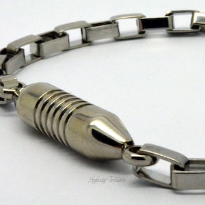 Könnte beinhalten: Ein silbernes Kettenarmband mit einem magnetischen Verschluss. Die Kette besteht aus quadratischen Gliedern mit einem hohlen Zentrum.