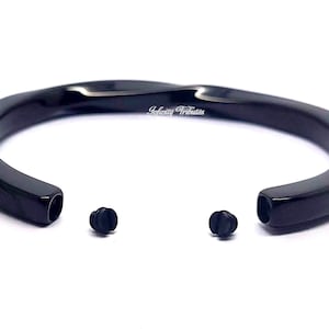 May include: Black metal bracelet with a twisted design. The bracelet has two screw-on closures.