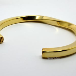 May include: A gold-toned twisted bangle bracelet with a screw closure.