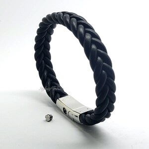 May include: A black leather braided bracelet with a silver clasp and a small silver screw.