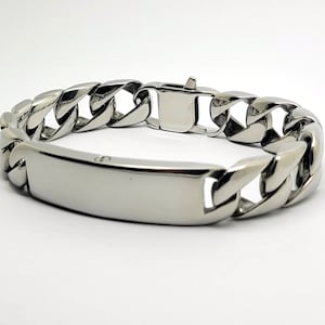 Puede incluir: Un brazalete de cadena de plata con una etiqueta rectangular. La etiqueta está en blanco y se puede grabar.