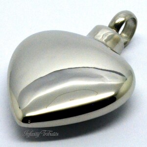 May include: A silver heart-shaped cremation pendant with a screw-on lid. The pendant is made of stainless steel and has a polished finish.