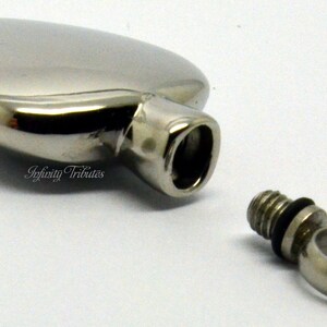 May include: A silver heart-shaped cremation urn with a threaded screw-on lid. The urn is open and the lid is separate.