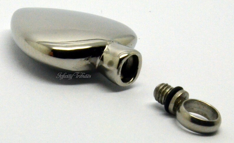 May include: A silver heart-shaped cremation urn with a threaded screw-on lid. The urn is open and the lid is separate.