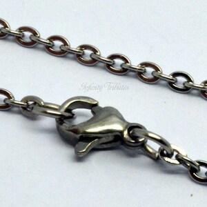 May include: A silver chain necklace with a lobster clasp closure. The chain is made of small, oval-shaped links.