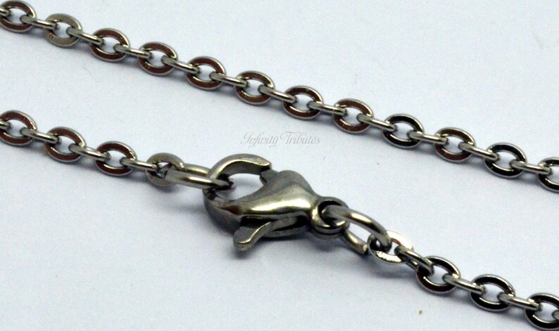 May include: A silver chain necklace with a lobster clasp closure. The chain is made of small, oval-shaped links.