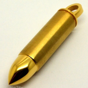 May include: A gold-coloured bullet-shaped pendant with a loop at the top. The pendant is made of metal and has a smooth, polished finish.