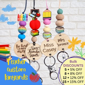May include: Teacher lanyards with wooden name tags and colourful beads. Each lanyard features a unique design with school-themed charms like apples, pencils, and books. The lanyards are designed for teachers and are available with bulk discounts.