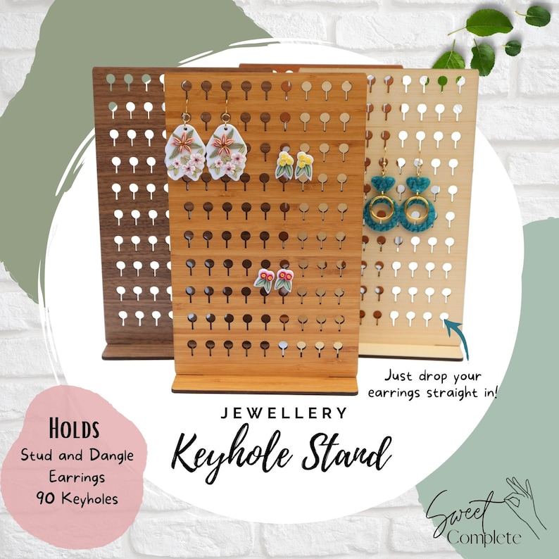 May include: A wooden keyhole earring stand with 90 holes. The stand is made of light brown wood and has a natural finish. It is shown with a variety of earrings in different colors and styles. The stand is labeled "Jewellery Keyhole Stand" and "Holds Stud and Dangle Earrings 90 Keyholes".