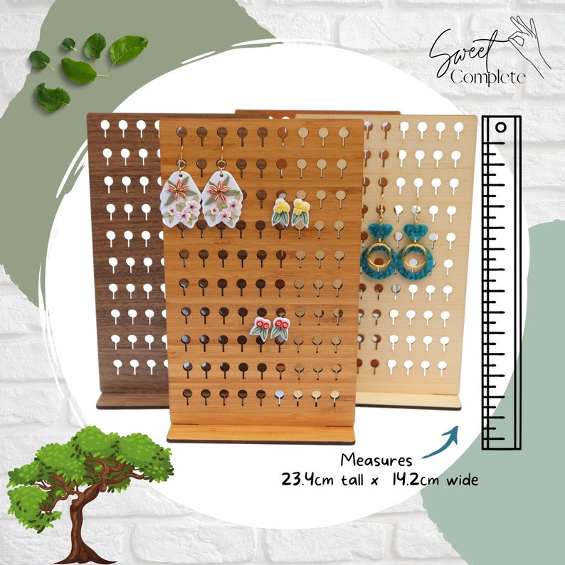 May include: Three wooden earring display stands with holes for hanging earrings. The stands are 23.4 inches tall and 14.2 inches wide. The stands are made of natural wood and have a light brown finish. The stands are shown with various earrings hanging from them. The text "Sweet Complete" is visible in the top right corner of the image.