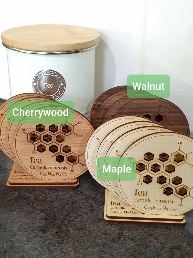May include: Set of four wooden coasters featuring a chemical structure of tea, with the text "Tea Camellia sinensis C50 H50 N4 O26" and the words "Cherrywood", "Walnut", "Maple" printed on the coasters.