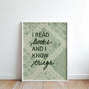 May include: A framed print with the text "I read books and I know things" in a stylish script. The background features a patchwork design in shades of green and white, creating a vintage aesthetic. The frame is white.